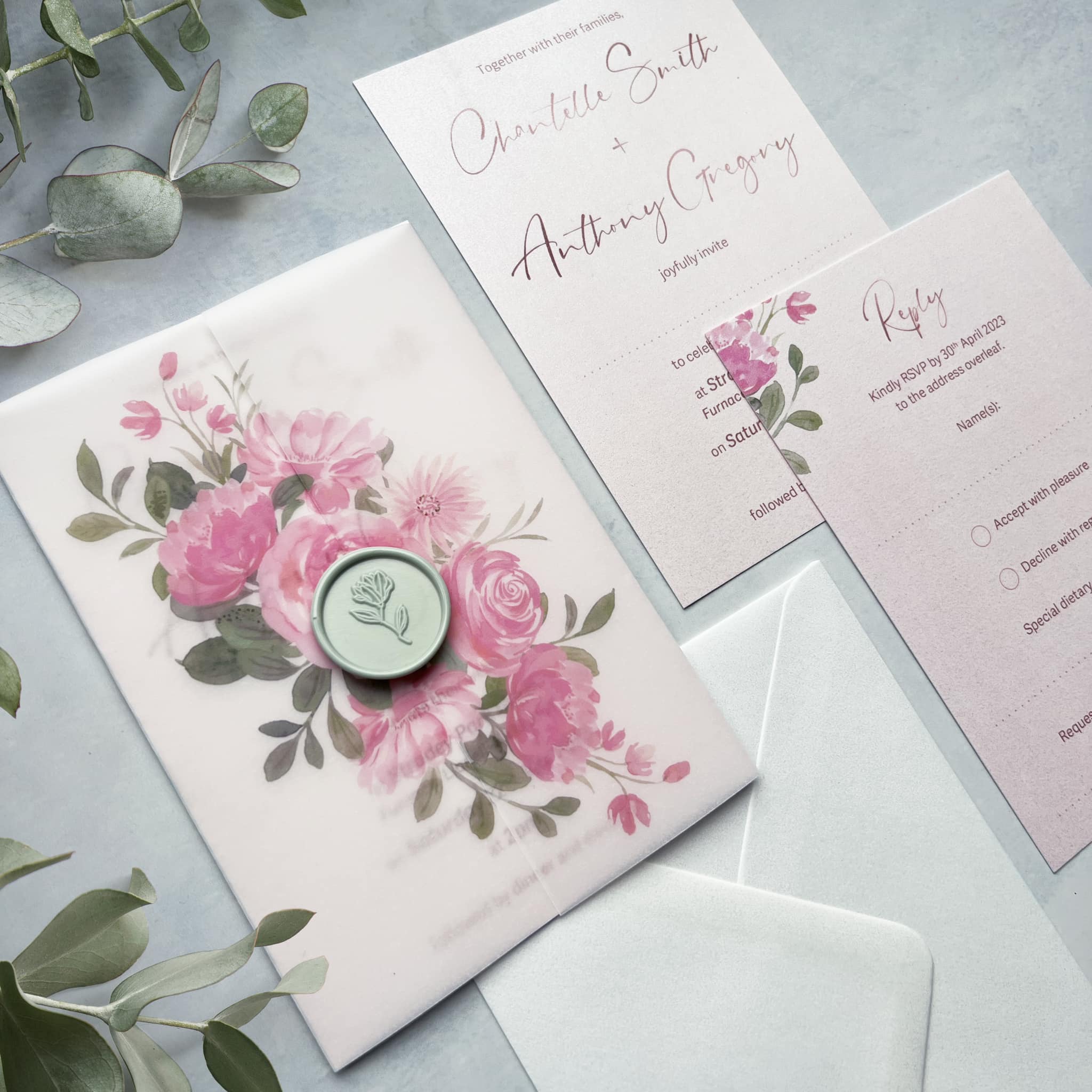 Blush pink invitation bundle wrapped in printed floral vellum.