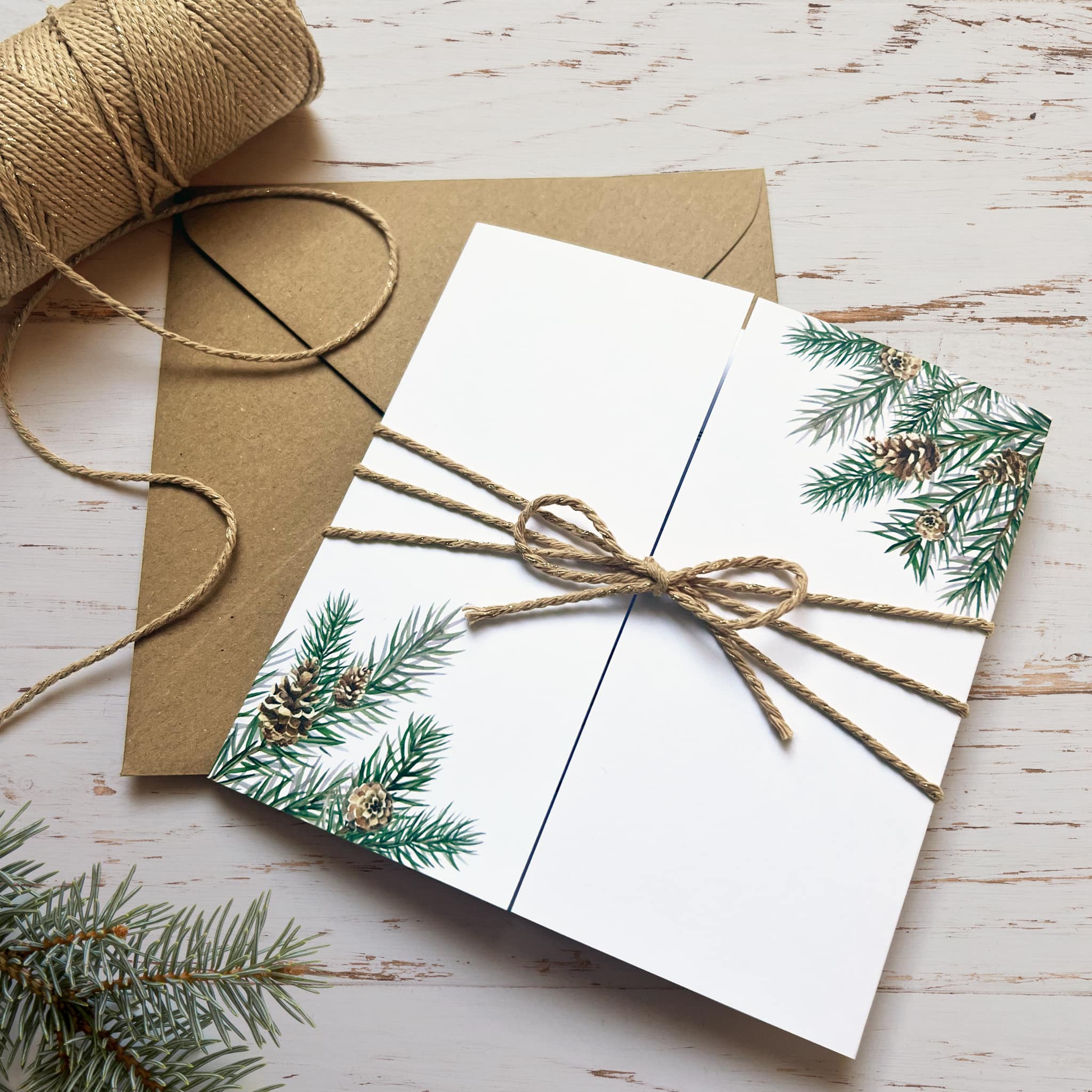 Winter wedding gatefold invitation featuring pine cones and branches, wrapped in twine.