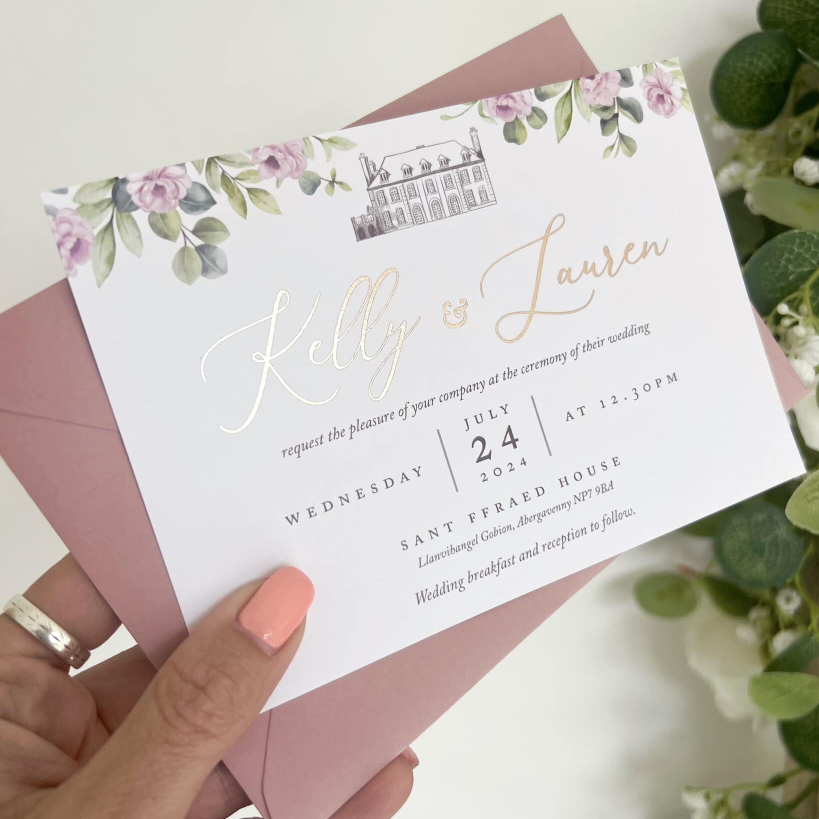 Flat wedding invitation card with rose gold foil names, dusky pink florals and a venue illustration of Sant Ffraed House.