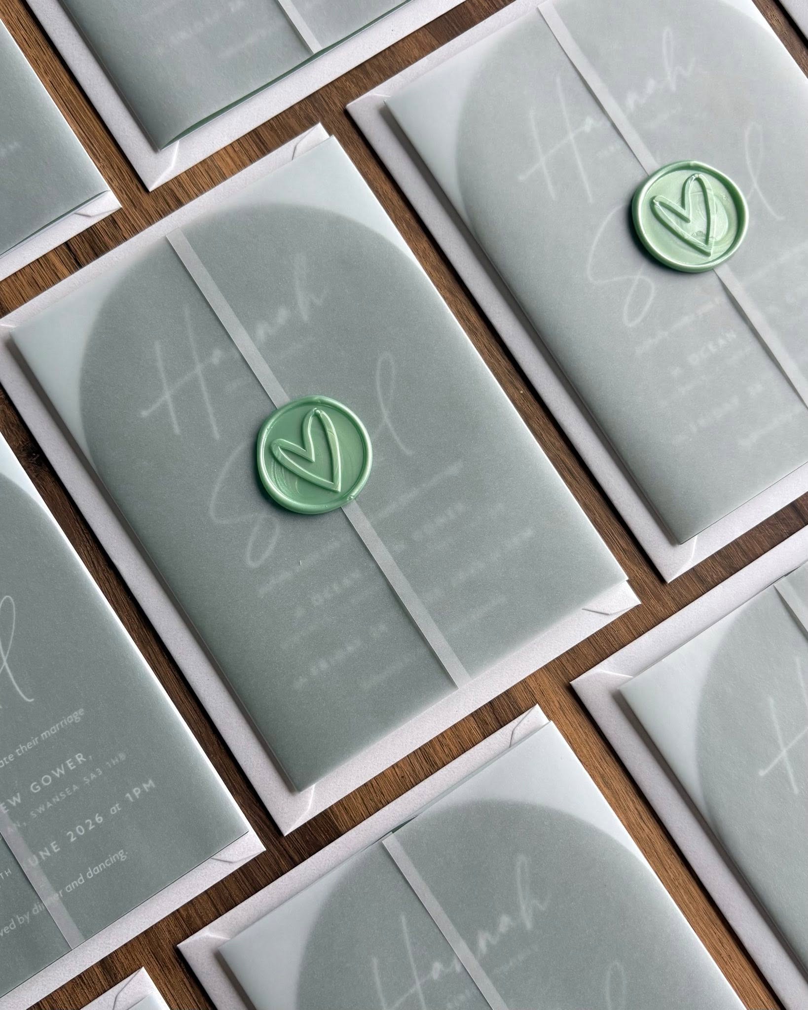 Green arch shaped wedding invitations wrapped in vellum